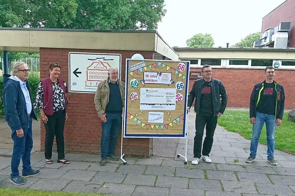 Spendenübergabe: sechs Personen vor der Jubiläumskarte des Schulvereins