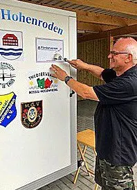 Mann klebt das För-BoHo-Logo auf den Kofferanhänger