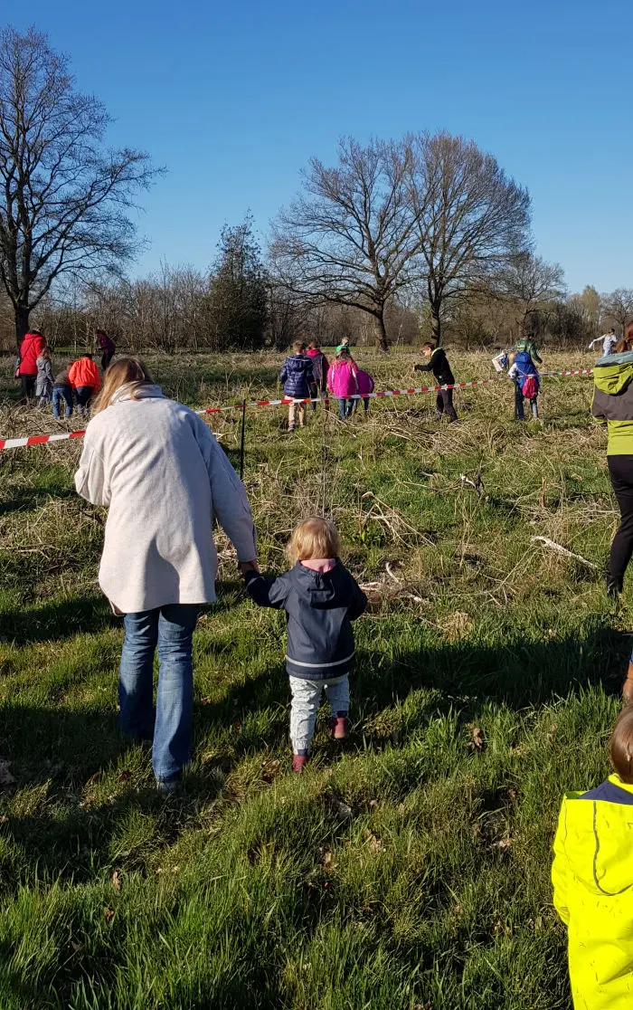 Kinder und Erwachsene bei der Ostereiersuche auf einer Wiese