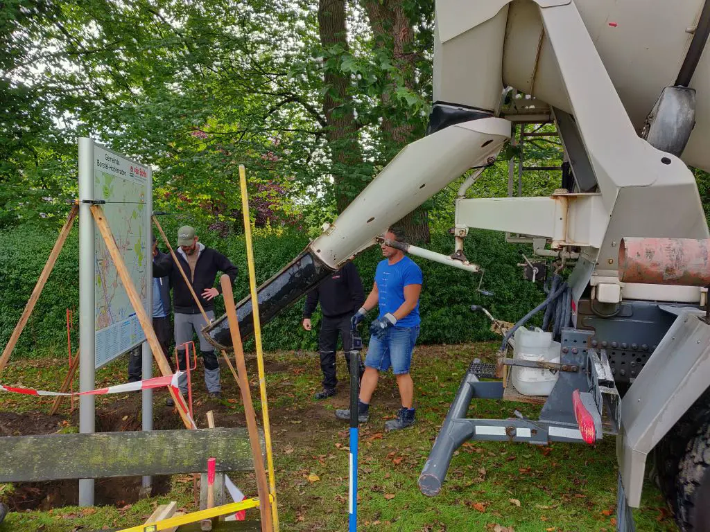 Betonmischer füllt die Fundamentgrube einer Info-Tafel