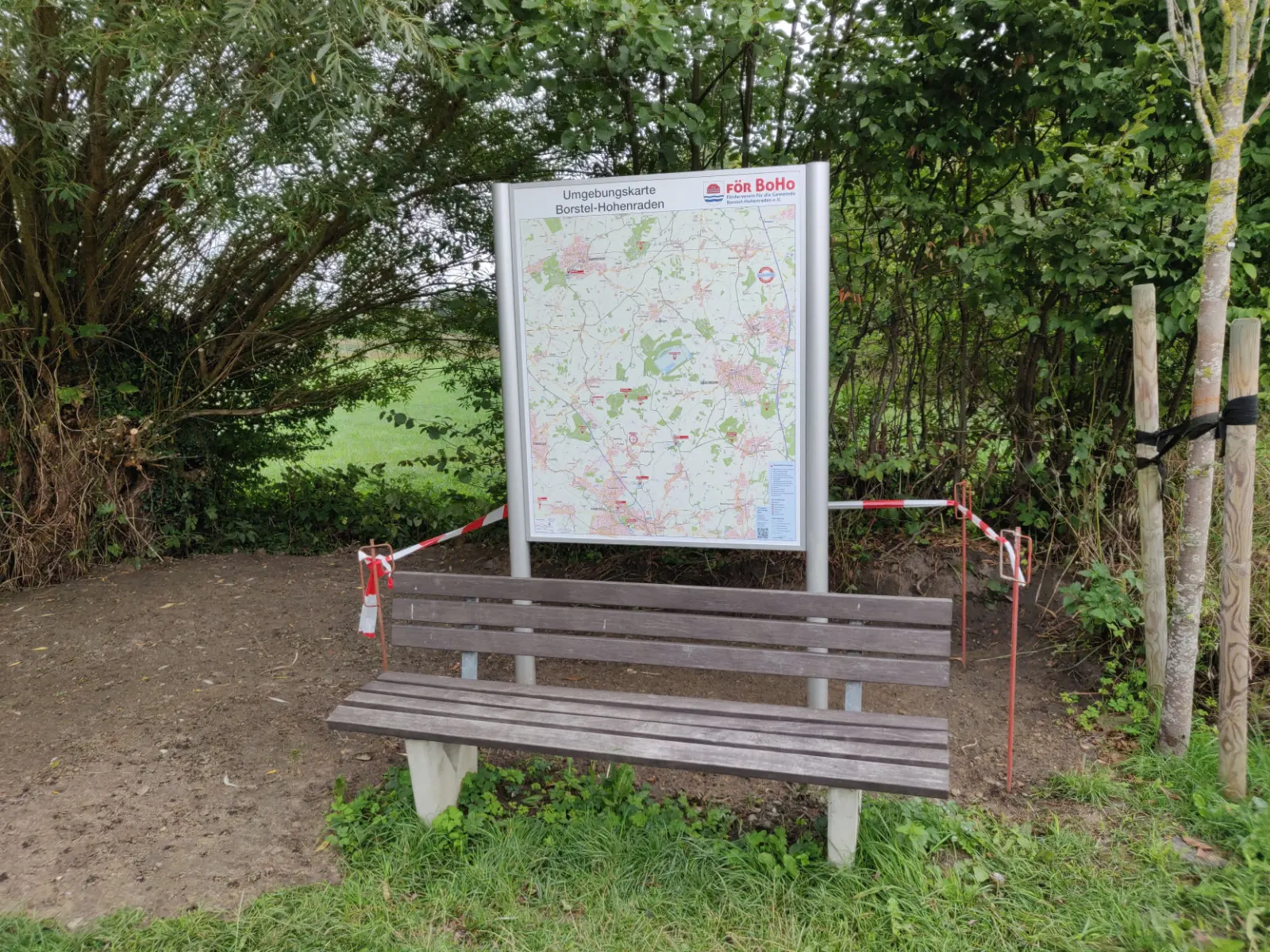 Info-Tafel mit Gemeindekarte neben einer Bank