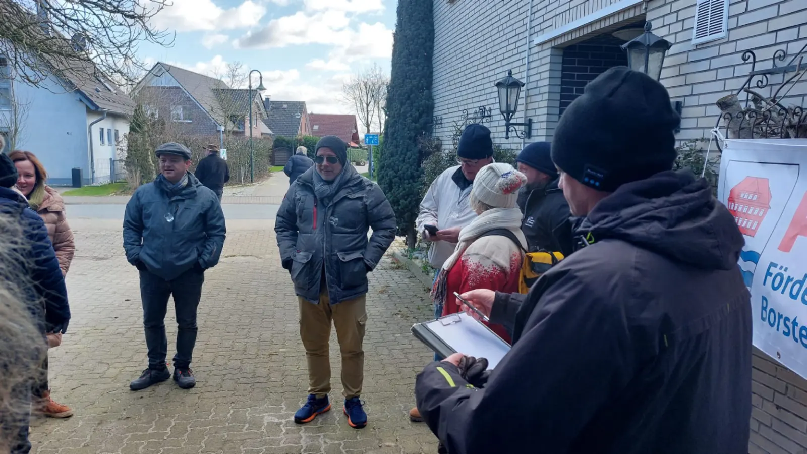 Gruppe auf einer Dorfstraße, Teilnehmer hält Notizen