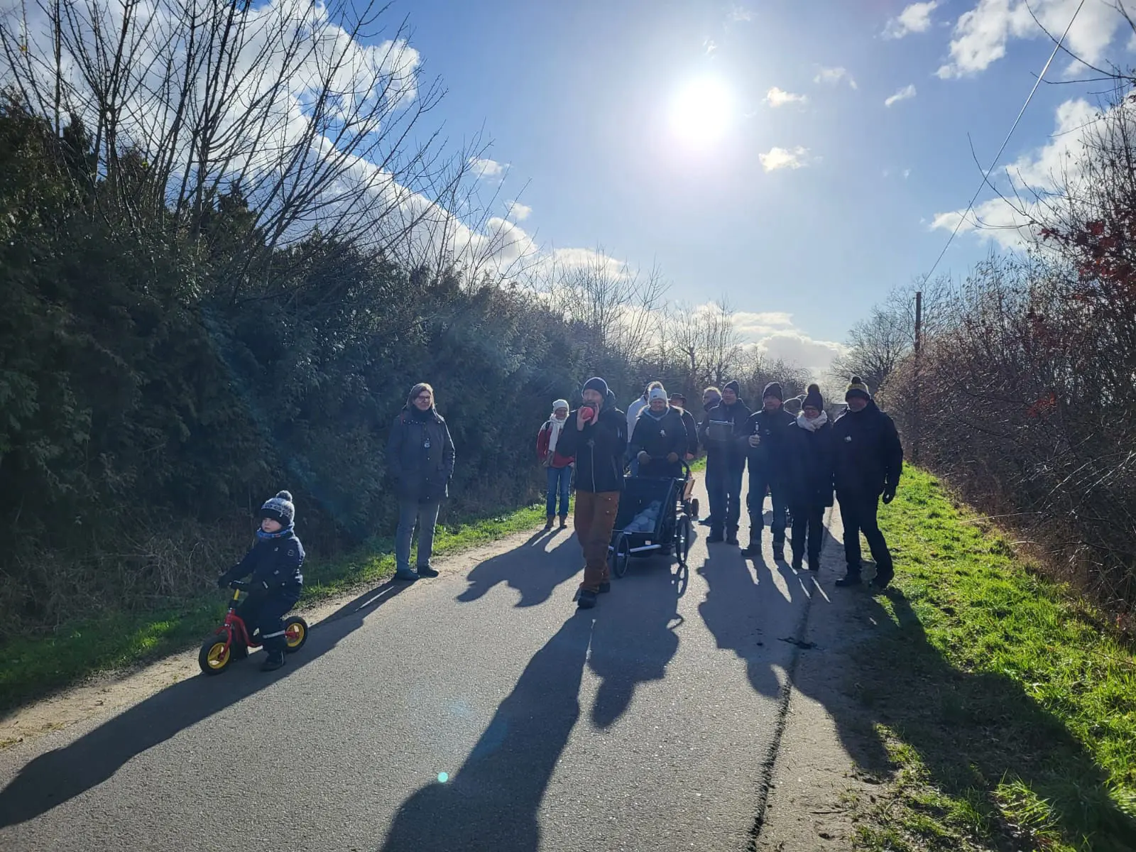 Boßeltour-Gruppe auf einem Weg im Gegenlicht, ein Kind auf dem Dreirad