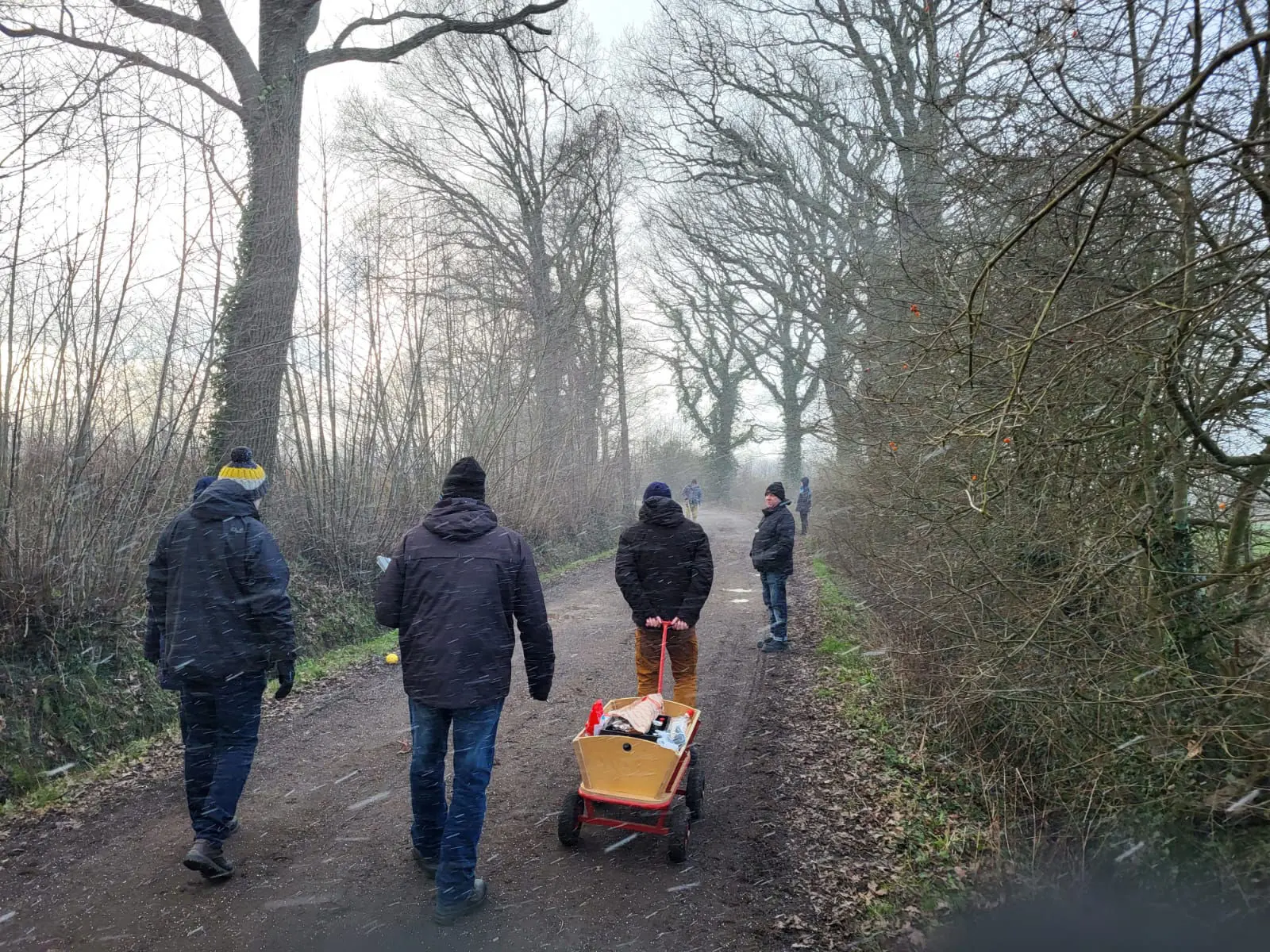Zwei Teilnehmer ziehen einen Bollerwagen über einen Feldweg