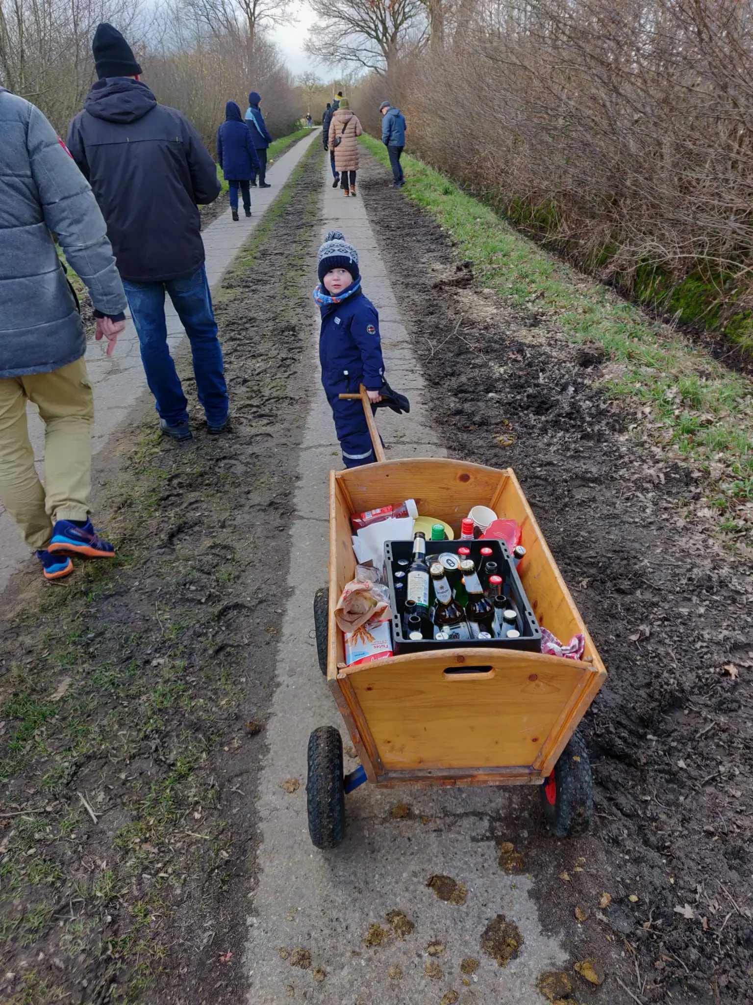 Bollerwagen mit Getränken auf einem Weg, Kind im Hintergrund