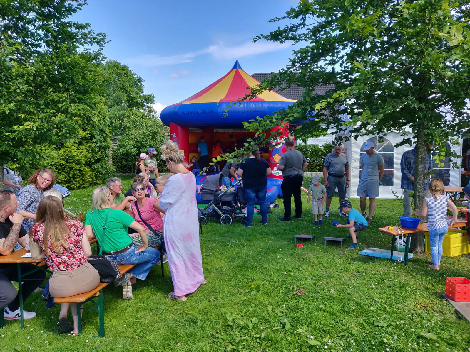 Familien auf Bierbänken, im Hintergrund eine Hüpfburg
