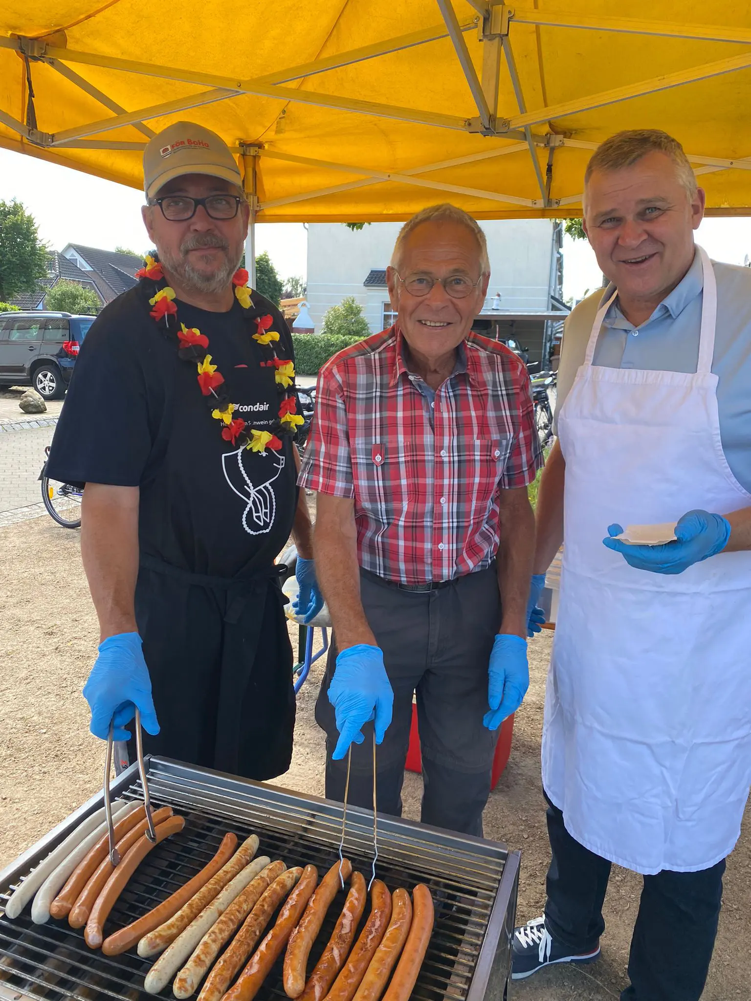 Drei Männer am Grill mit Bratwürsten