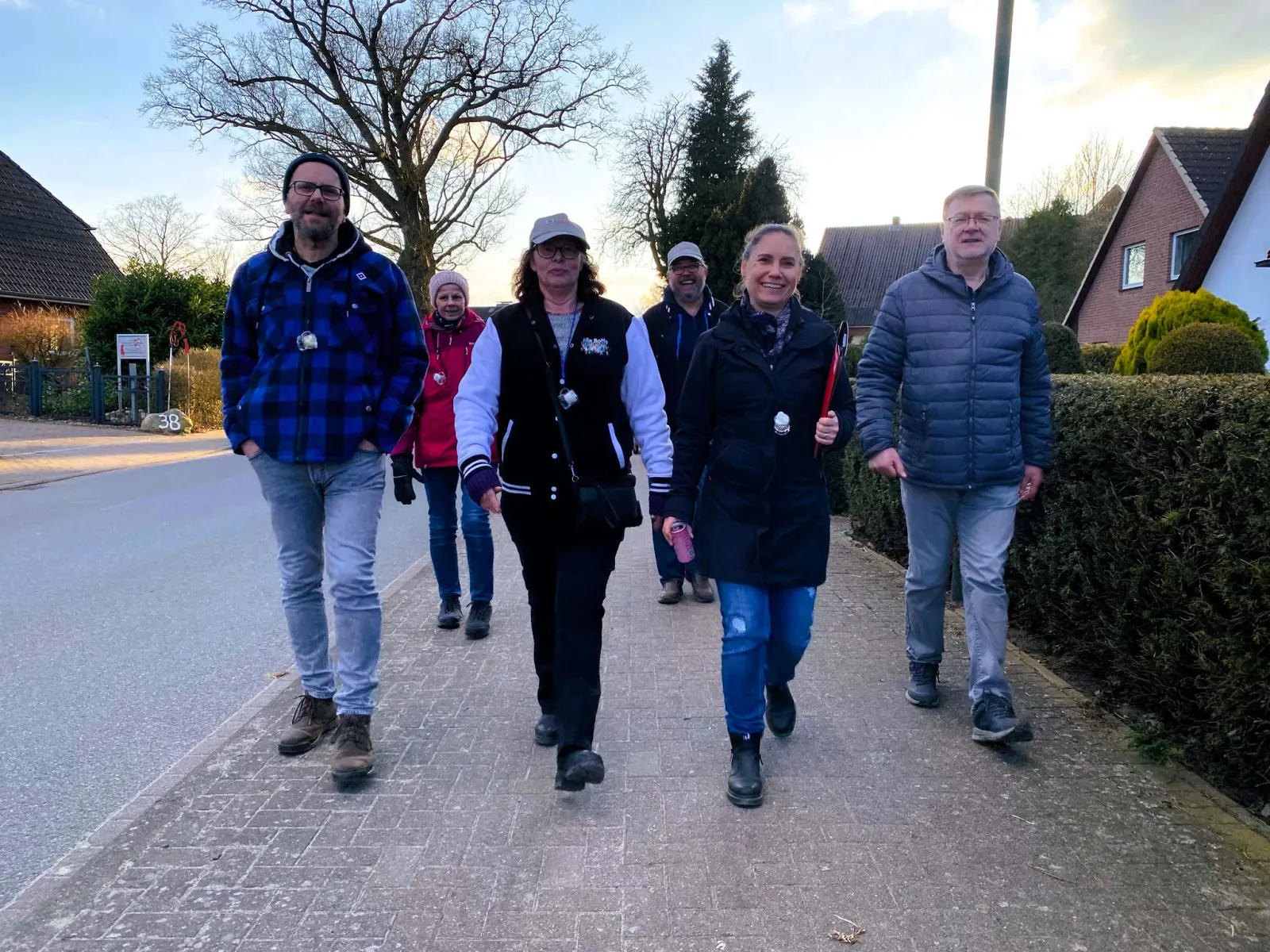 Fünf Teilnehmende gehen eine Dorfstraße entlang