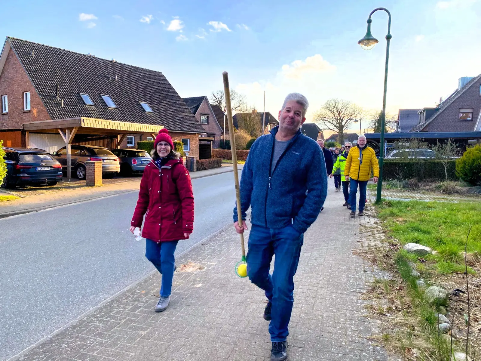Teilnehmer mit Boßelkugel und Stab auf der Dorfstraße