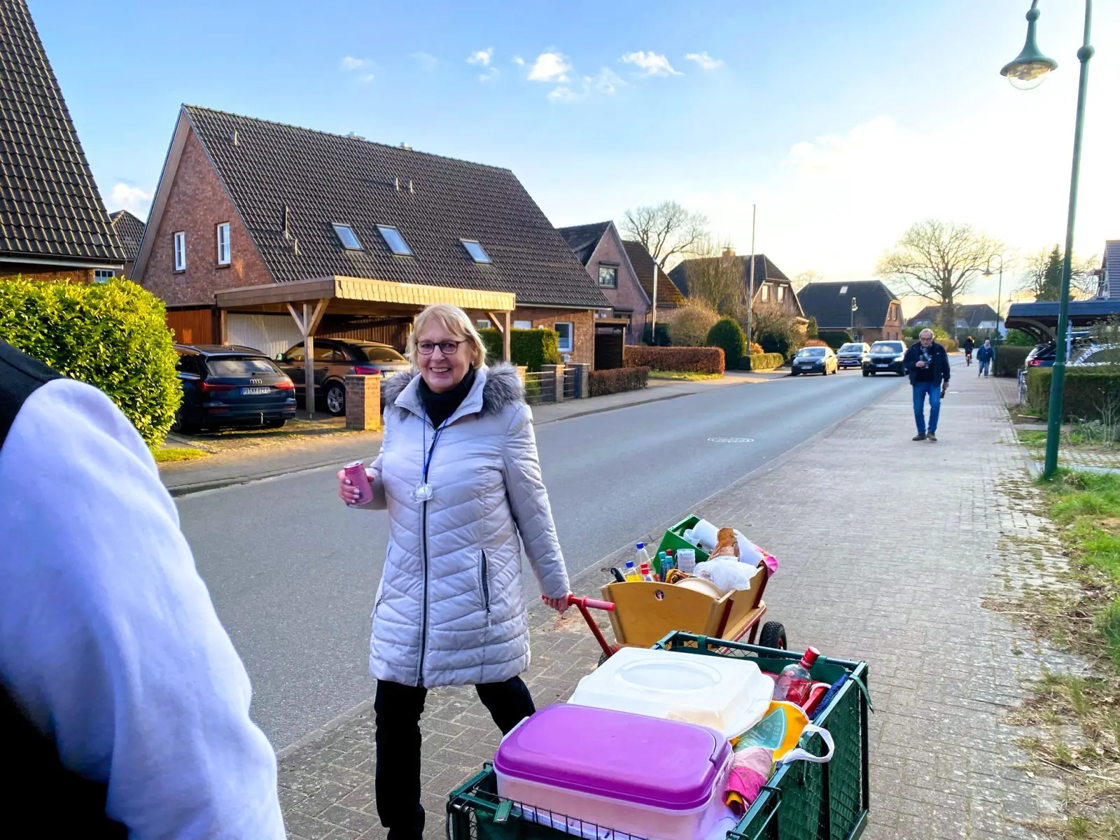 Frau mit Bollerwagen und Proviant auf der Dorfstraße