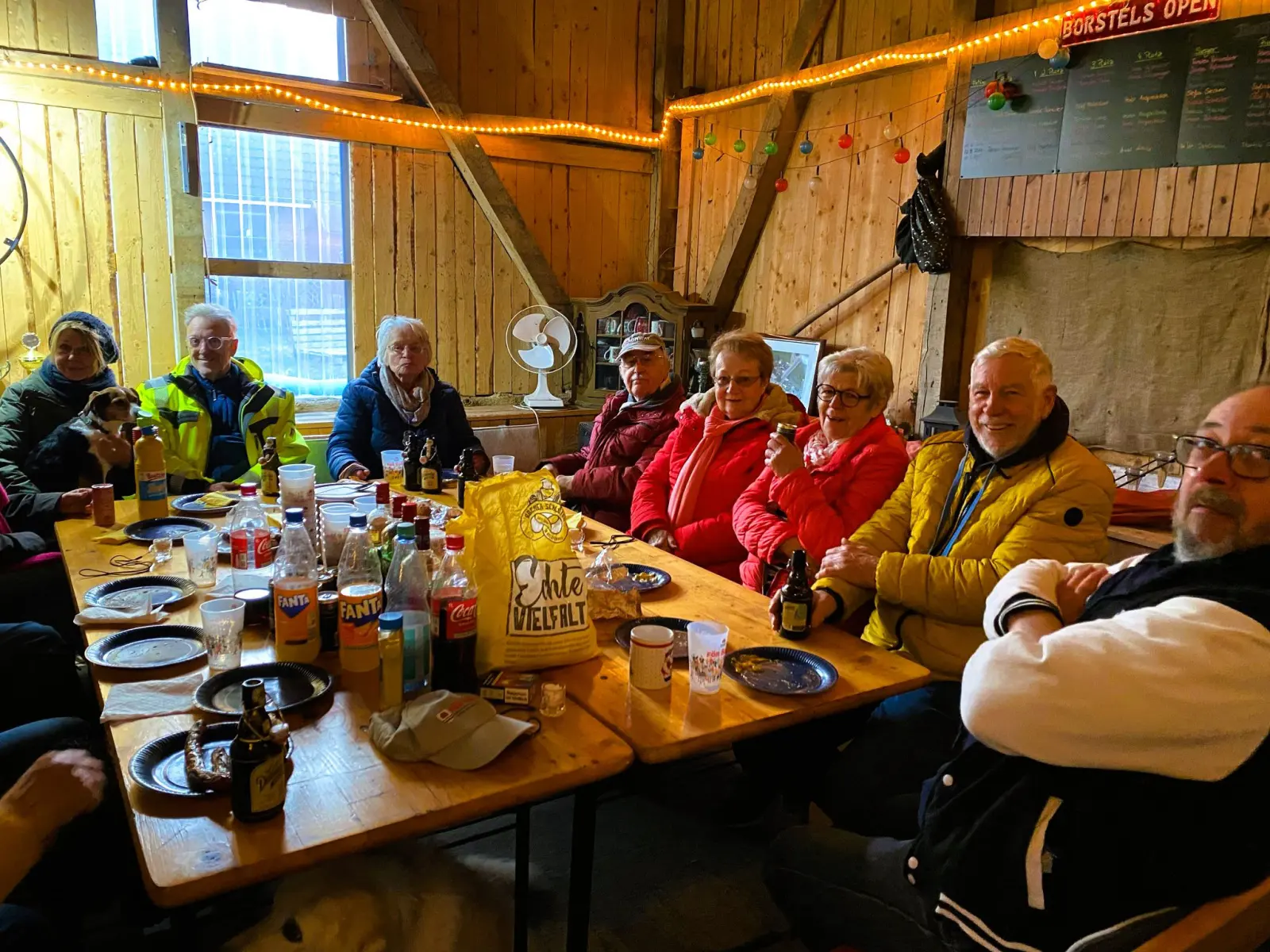 Teilnehmende sitzen zum gemeinsamen Essen an langen Tischen